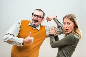 Nerdy man is showing to a beautiful woman how strong he is and she is impressed photo
