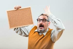 Nerdy businessman is in panic because of something while holding empty cork board photo