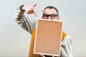 Nerdy businessman is showing empty cork board photo