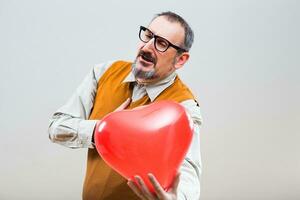 Cheerful nerdy man is giving to his girlfriend heart shape balloon photo