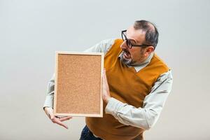 Nerdy businessman is shocked because of something while holding empty cork board photo