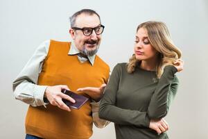 Nerdy man is showing to his beautiful wife that he doesn't have any more money and she is disappointed photo