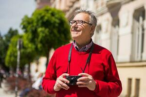 Senior man tourist enjoys photographing at the city photo