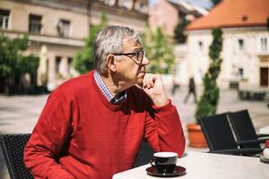 Sad senior man thinking about something while sitting at the bar photo