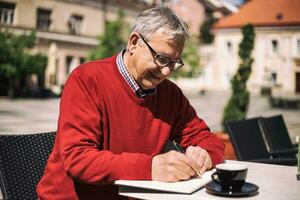 Senior businessman enjoys working and drinking coffee at the bar photo