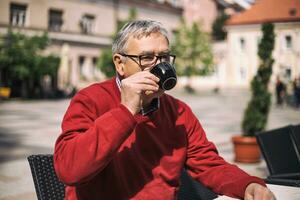 Senior man enjoys drinking coffee at the bar photo