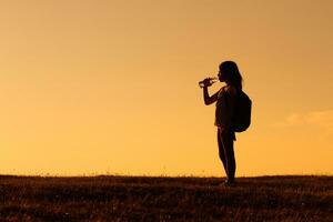 Little girl hiker drinking water photo