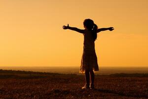 silueta de pequeño niña saludo el puesta de sol foto