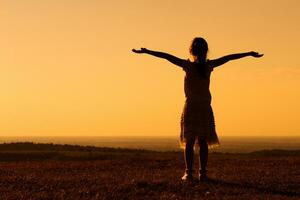 Silhouette of little girl greeting the sunset photo