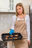 Sad housewife holding tray with burnt cookies photo