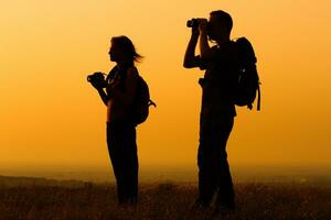 Pareja con mochila acecho el puesta de sol foto