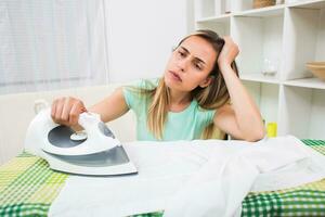 Beautiful woman is tired of ironing every day photo