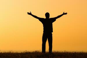 Silhouette of a  man  greeting the sunset photo