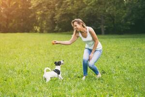 Beautiful woman enjoys playing with her cute dog Jack Russell Terrier in the nature. photo