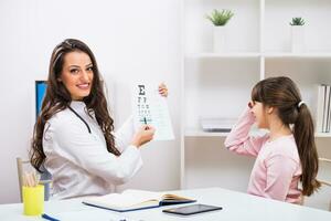 Female doctor doing eye exam with child at the medical office photo