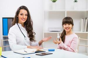 Female doctor showing how to use inhaler to a child at the medical office photo