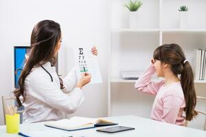 Female doctor doing eye exam with child at the medical office photo