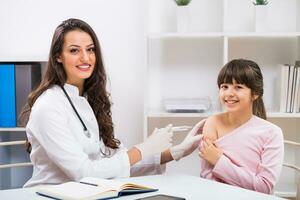 hembra médico dando inyección a un niño a médico oficina foto