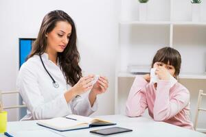 Female doctor checking temperature of sick child at medical office photo