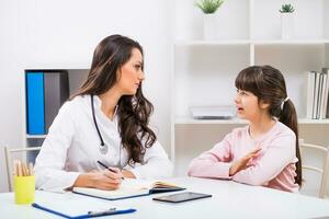 Female doctor and child talking at the medical office photo