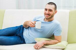 joven hombre disfruta Bebiendo café a hogar foto