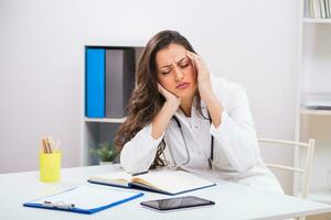 Female doctor is having headache while working at her office photo