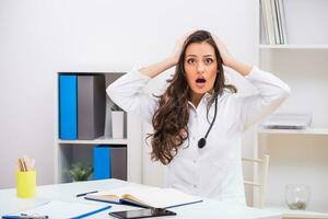 Female doctor is in panic because of something while she is working at her offic photo