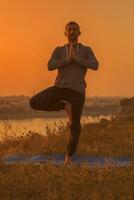 Man doing yoga on sunset with city view photo