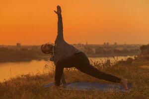 Man doing yoga on sunset with city view photo