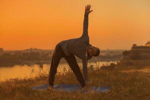 Man doing yoga on sunset with city view photo