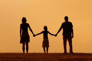 Parents enjoy watching sunset with their daughter photo