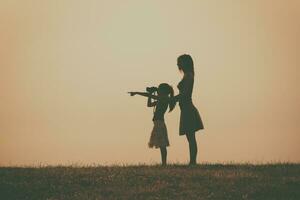 Little girl is standing with her mother outdoor and watching with binoculars nature photo