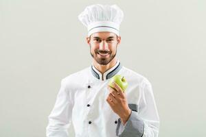 Chef is holding apple and orange on gray background. photo