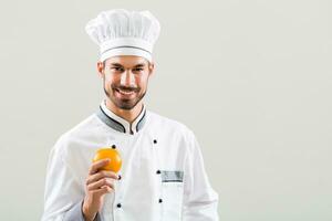 Chef is holding  orange on gray background. photo