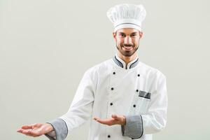 sonriente cocinero demostración Bienvenido gesto en gris antecedentes foto