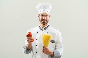 Chef is holding tomato and spaghetti on gray background. photo
