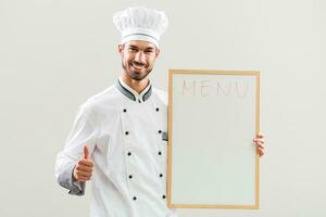 Chef is showing whiteboard and thumb up on gray background. photo