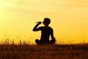 Silhouette of woman drinking water after exercise photo