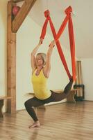 Woman doing aerial yoga in the fitness studio photo