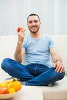 joven hombre comiendo manzana a hogar foto