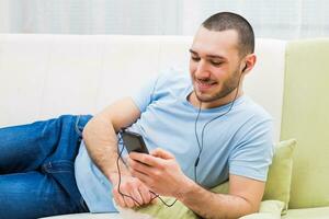 joven hombre es escuchando música desde su móvil teléfono foto