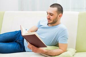 joven hombre disfruta leyendo libro a su hogar foto