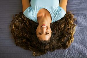 Portrait of beautiful woman with long curly hair resting on bed photo