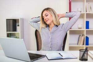 Businesswoman stretching while working in her office photo