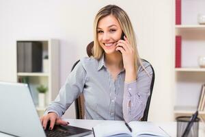 Businesswoman using mobile phone while working in her office photo