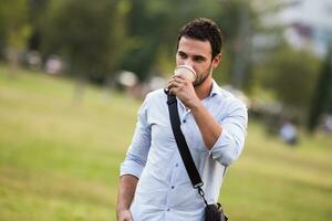 joven empresario es Bebiendo café y descansando desde trabajo a el parque foto