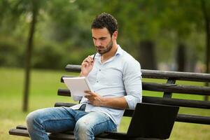 Young businessman is sitting and thinking about his business while sitting at the park photo