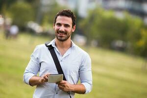 Young businessman is using digital tablet at the park photo