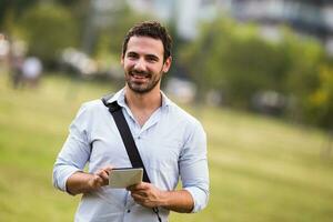 joven empresario es utilizando digital tableta a el parque foto