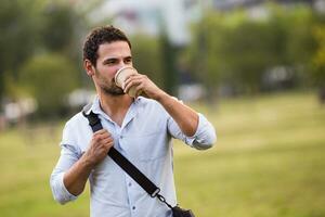 Young businessman is drinking coffee and resting from work at the park photo